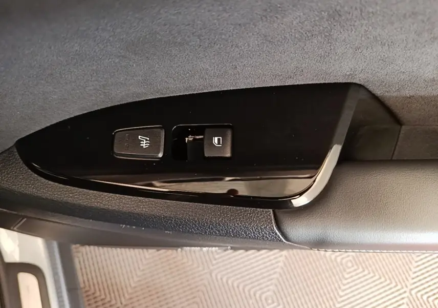 Gros plan sur les commandes de verrouillage et chauffage du siège côté conducteur d’un KIA Sportage gris clair 2022.