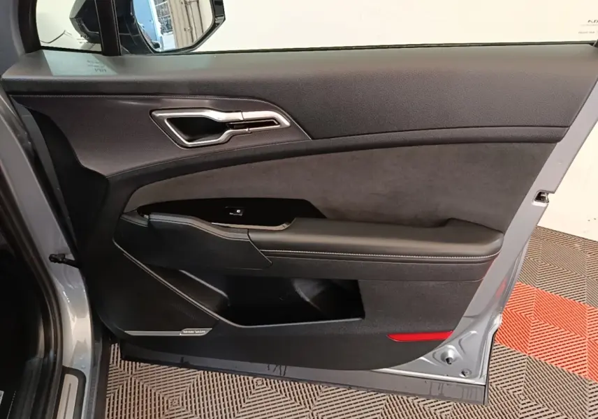 Vue intérieure de la porte côté conducteur gris clair du Kia Sportage 2022 avec garniture noire et haut-parleur Harman Kardon.