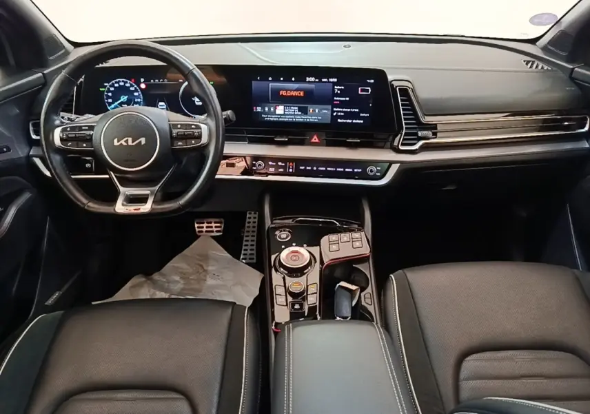 Vue intérieure avant du tableau de bord et volant noir du Kia Sportage hybride rechargeable 2022 avec écran tactile large.