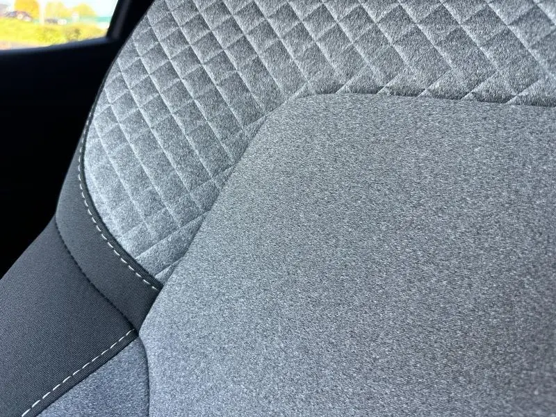 Gros plan sur le tissu gris à motif 3D du siège avant de la Renault Clio 2025, soulignant la texture et les surpiqûres.