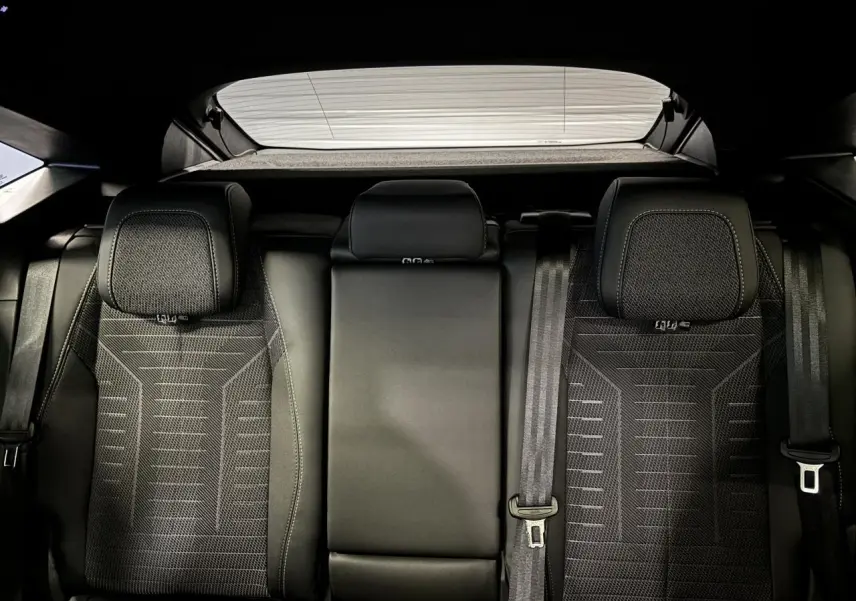 Vue arrière intérieure des sièges arrière en tissu noir avec surpiqûres et ceintures de sécurité du Peugeot 3008 Hybrid 2025.
