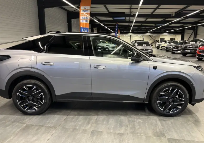 Vue de profil côté gauche d’un Peugeot 3008 gris Artense avec jantes alliage noires et toit noir en showroom.