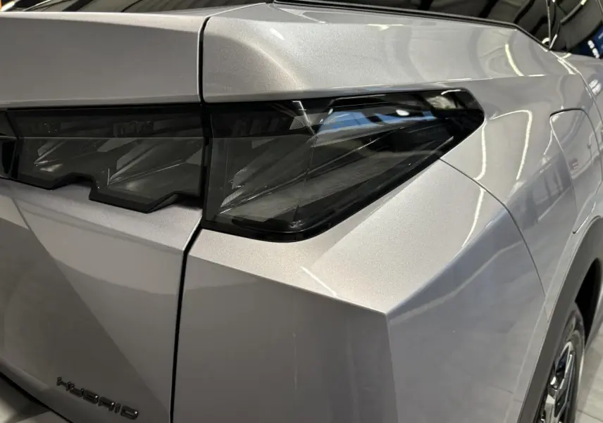 Gros plan sur le feu arrière droit et la carrosserie gris Artense du Peugeot 3008 Hybrid 2025, avec détails anguleux.