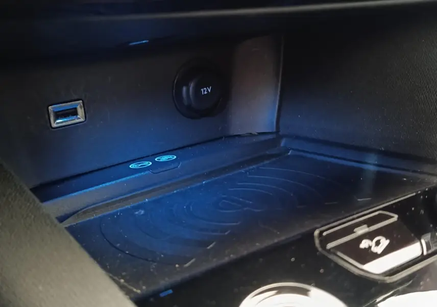 Gros plan sur la console centrale noire du Peugeot 5008 2019 avec prise USB, prise 12V et zone de charge sans fil.
