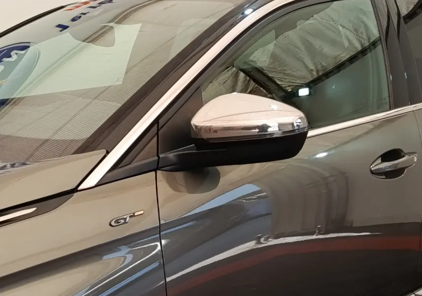 Détail du côté gauche d’un Peugeot 5008 GT gris clair avec rétroviseur chromé et badge GT visible.