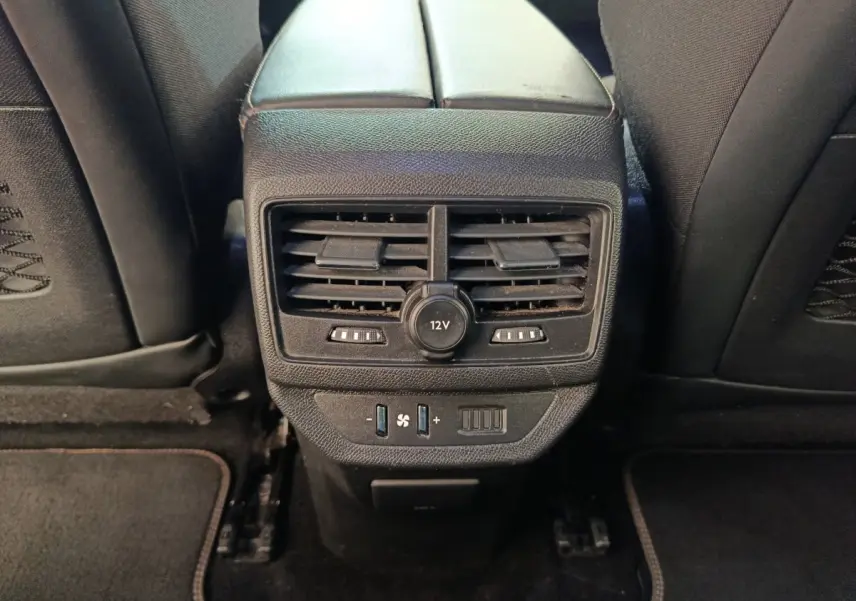 Vue rapprochée de la console centrale arrière noire avec aérateurs et prise 12V du Peugeot 5008 gris clair.