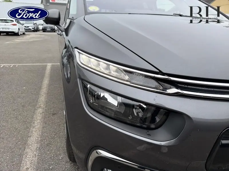 Gros plan sur l'avant gauche d'une Citroën C4 Spacetourer gris Platinium, mettant en valeur ses phares fins et la calandre chromée.