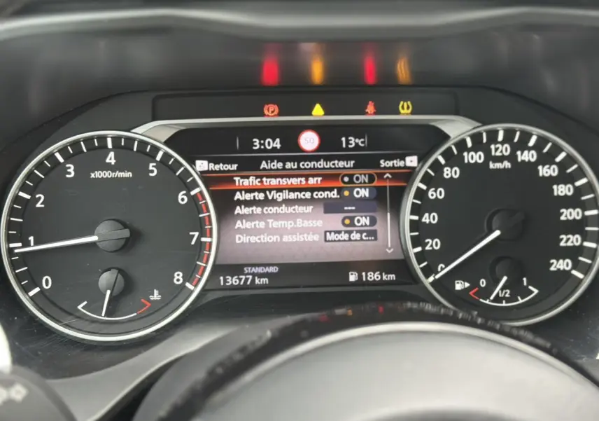 Tableau de bord du Nissan Qashqai 2025, affichage digital central avec alertes et compte-tours à gauche, vitesse à droite.