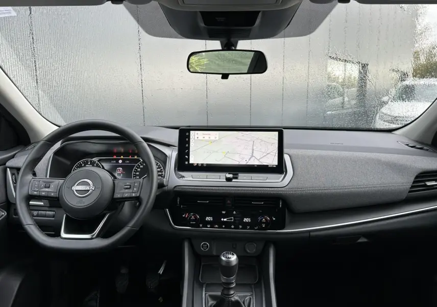 Vue intérieure avant du Nissan Qashqai 2025 noir nacré, avec volant multifonction, écran tactile et boîte manuelle.