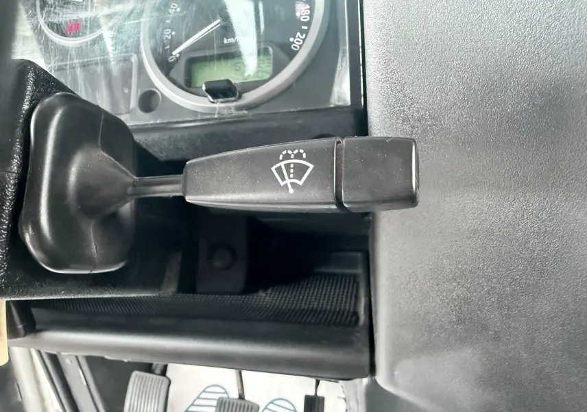 Gros plan sur le levier de commande d’essuie-glace noir dans l’habitacle gris foncé du Land Rover Defender blanc de 2007.