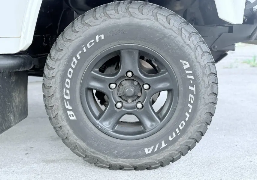 Gros plan sur la roue avant droite du Land Rover Defender blanc de 2007 avec pneu BFGoodrich All-Terrain.