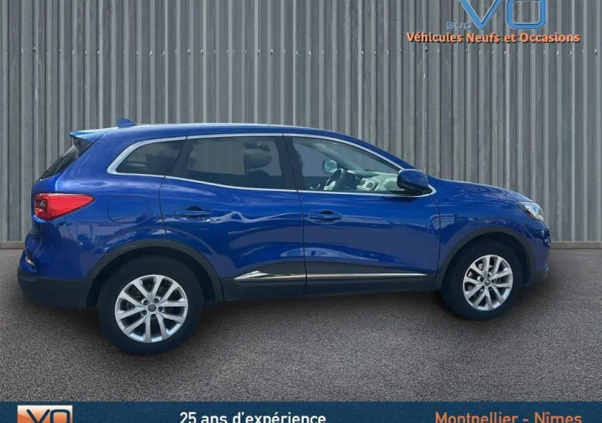 Profil côté gauche d'un Renault Kadjar TCe 140 FAP Business bleu foncé avec jantes alliage 17 pouces sur fond urbain.