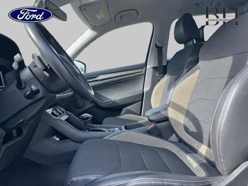 Vue intérieure côté conducteur du Skoda Kodiaq 2023, sièges en suède cuir noir avec accoudoir central.