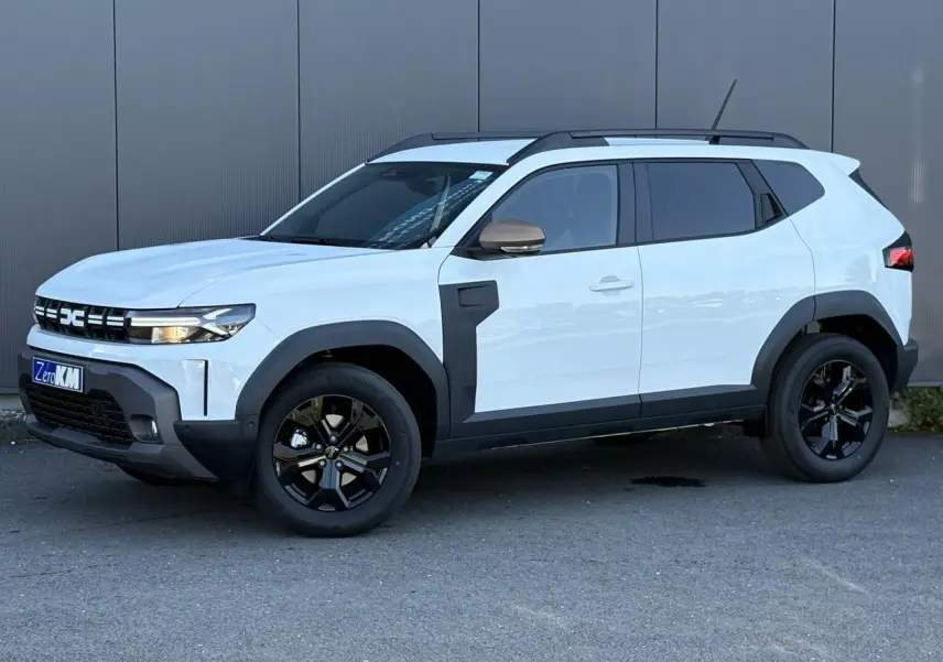 Dacia Duster Blanc Glacier en vue 3/4 avant droit, avec jantes noires et détails noirs contrastants sur les ailes.