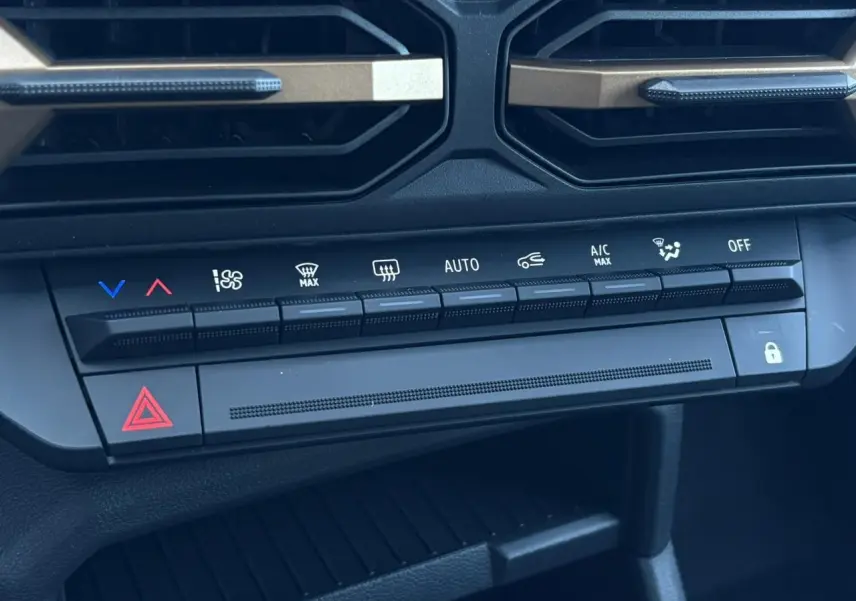 Gros plan sur la console centrale du Dacia Duster blanc Glacier 2026, montrant les commandes de climatisation et sécurité.