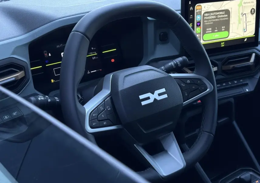 Vue intérieure rapprochée du volant et tableau de bord digital du Dacia Duster 2026 avec écran tactile central.