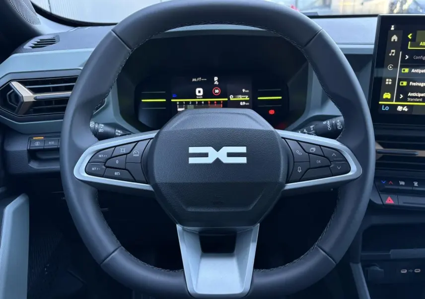 Vue rapprochée du volant noir du Dacia Duster 2026 avec tableau de bord digital et écran tactile central.
