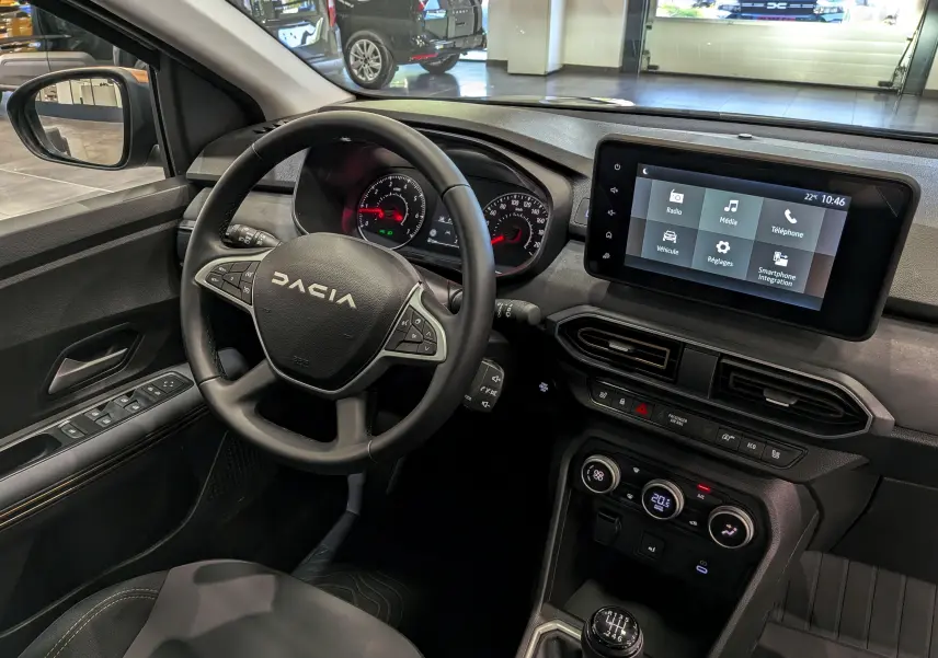 Vue intérieure côté conducteur du tableau de bord et volant du Dacia Sandero Stepway 2025 avec écran tactile et levier de vitesses manuel.
