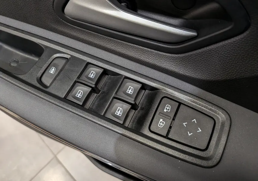 Détail des commandes des vitres électriques et réglages des rétroviseurs sur la porte côté conducteur d'une Dacia Sandero Stepway gris schiste.