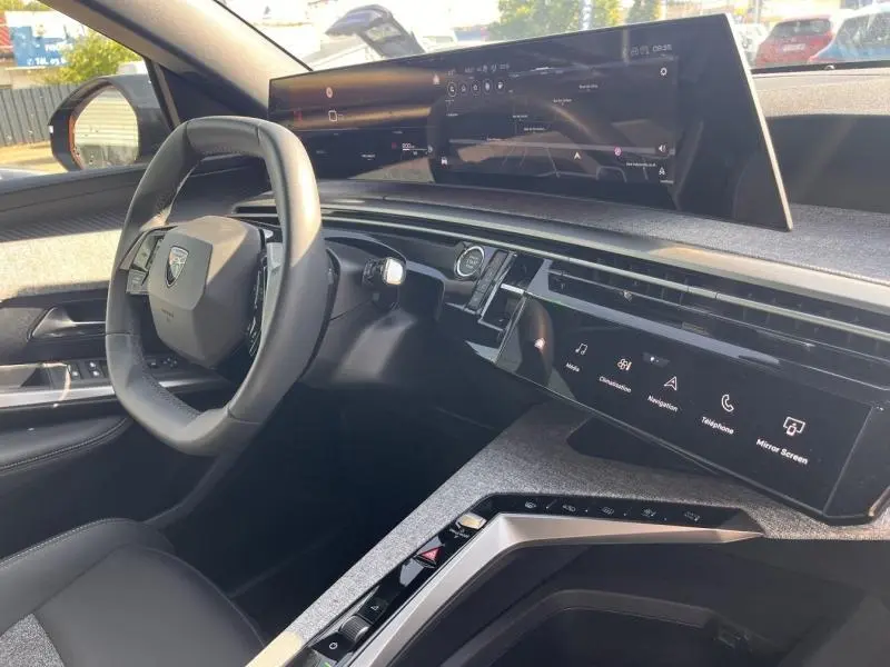 Vue intérieure côté conducteur du Peugeot 3008 1.2 Hybrid 2025, montrant le tableau de bord numérique et le volant cuir multifonction.