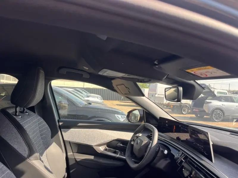 Vue intérieure côté conducteur du Peugeot 3008 Hybrid 2025 avec sièges tissu gris et tableau de bord moderne.
