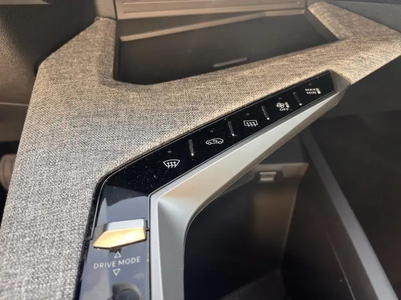 Vue rapprochée des commandes centrales avec tissu gris et boutons tactiles du Peugeot 3008 Hybrid 2025.
