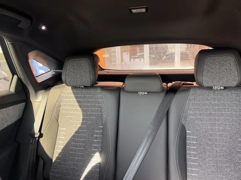 Vue arrière intérieure du Peugeot 3008 1.2 Hybrid 2025, sièges tissu gris Crispy/TEP avec appuis-tête et ceinture noire.