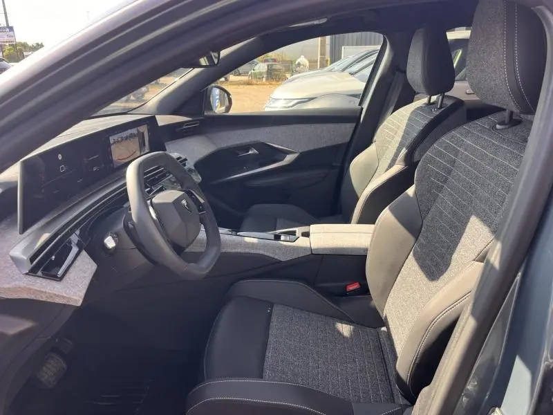 Vue intérieure côté conducteur du Peugeot 3008 gris Artense, mettant en valeur les sièges bi-matière et le tableau de bord numérique.