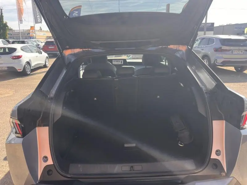 Coffre ouvert vu de l'arrière d'un Peugeot 3008 gris Artense avec banquette arrière rabattable visible.
