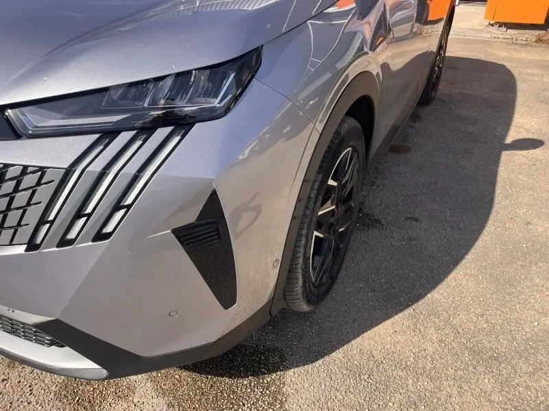 Vue 3/4 avant droit du Peugeot 3008 gris Artense, mettant en valeur ses phares LED et la calandre distinctive.