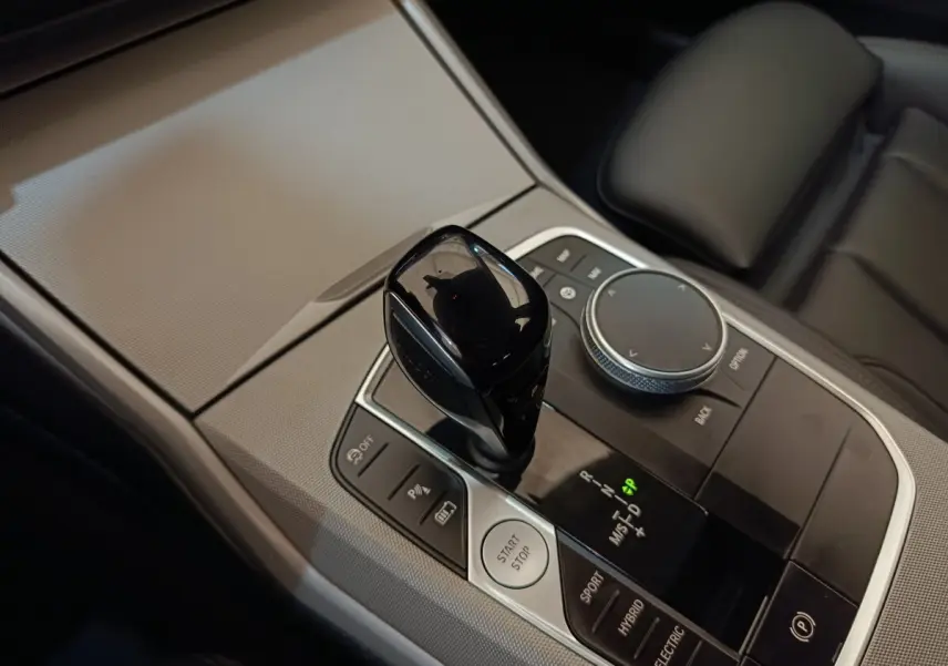Gros plan sur la console centrale noire et argentée avec levier de vitesses et bouton démarrage d’une BMW Série 3 blanche.