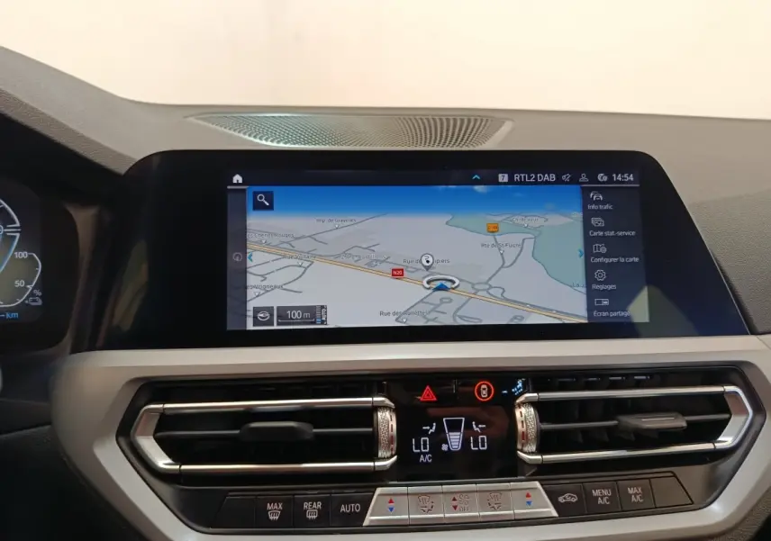 Vue intérieure du tableau de bord de la BMW Série 3 320e hybride avec écran tactile de navigation et commandes climatisation.