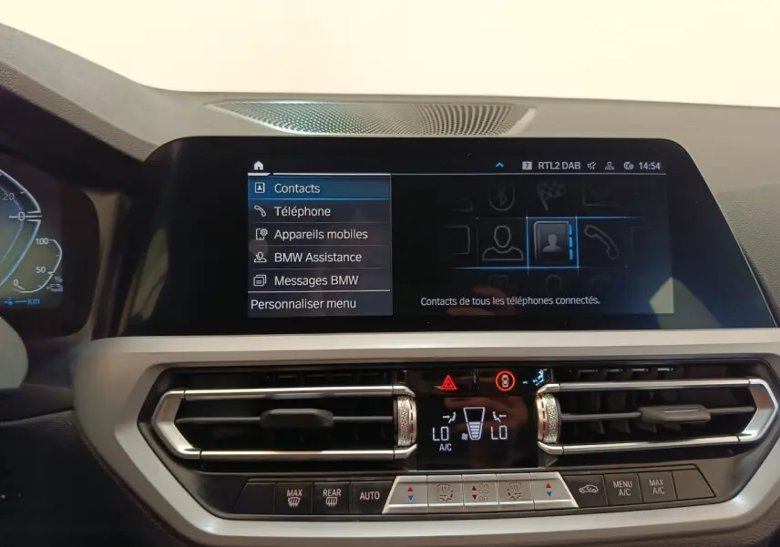 Vue rapprochée de l’écran tactile central et de la console de climatisation d’une BMW Série 3 blanche, intérieur moderne.
