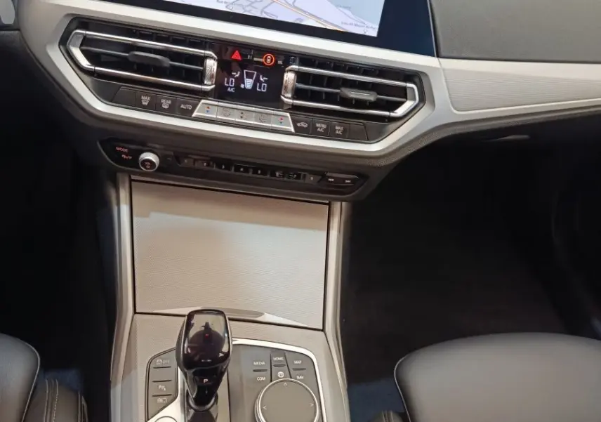 Vue intérieure centrée sur la console centrale et l’écran tactile du tableau de bord de la BMW Série 3 320e hybride.