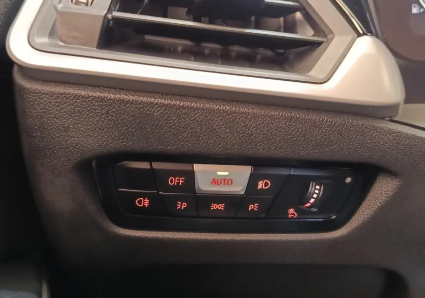 Détail du tableau de bord côté gauche de la BMW Série 3 320e blanche, avec commandes d’éclairage et ventilation.
