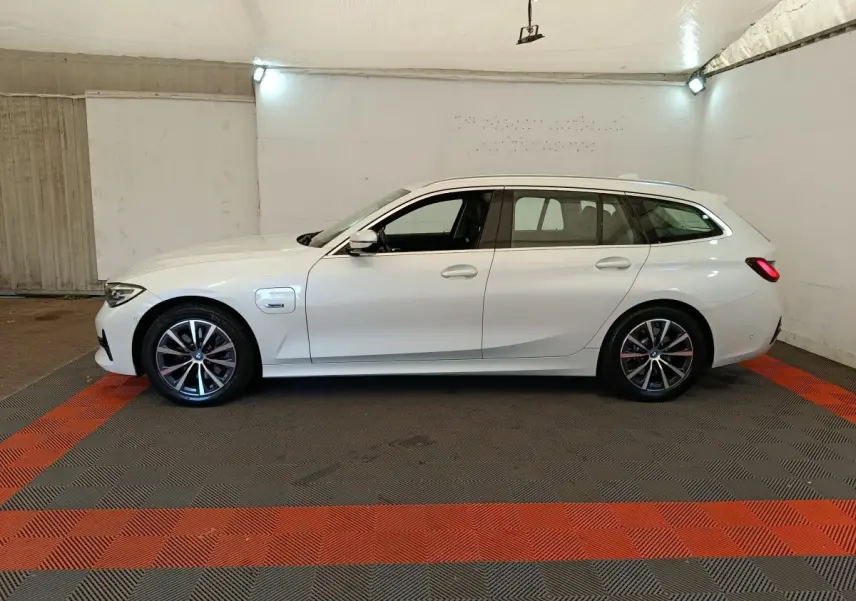 BMW Série 3 320e hybride blanche vue de profil côté gauche dans un garage avec jantes alliage et toit ouvrant.