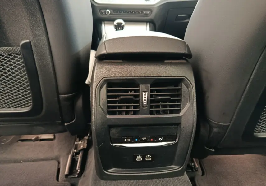 Vue rapprochée de la console centrale arrière noire avec bouches d’aération et ports USB dans BMW Série 3 blanche.