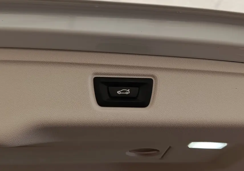 Bouton d'ouverture électrique du coffre sur la trappe intérieure d'une BMW Série 3 blanche hybride rechargeable.