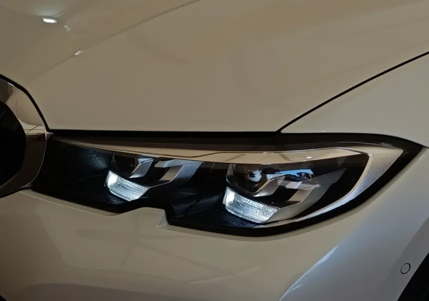 Gros plan sur le phare avant droit blanc d’une BMW Série 3 320e hybride rechargeable avec éclairage LED distinctif.