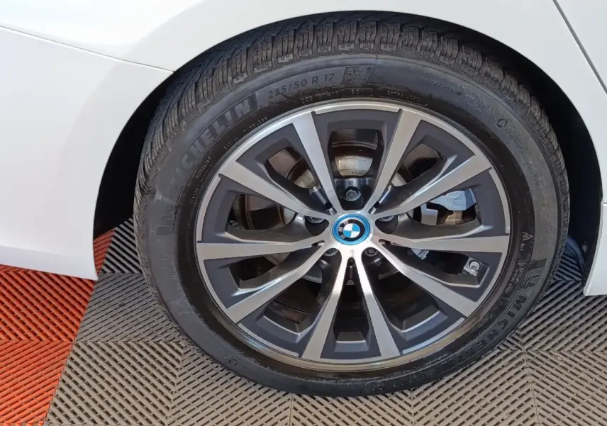 Gros plan sur la roue avant droite blanche d’une BMW Série 3 320e hybride avec jante alliage gris foncé.