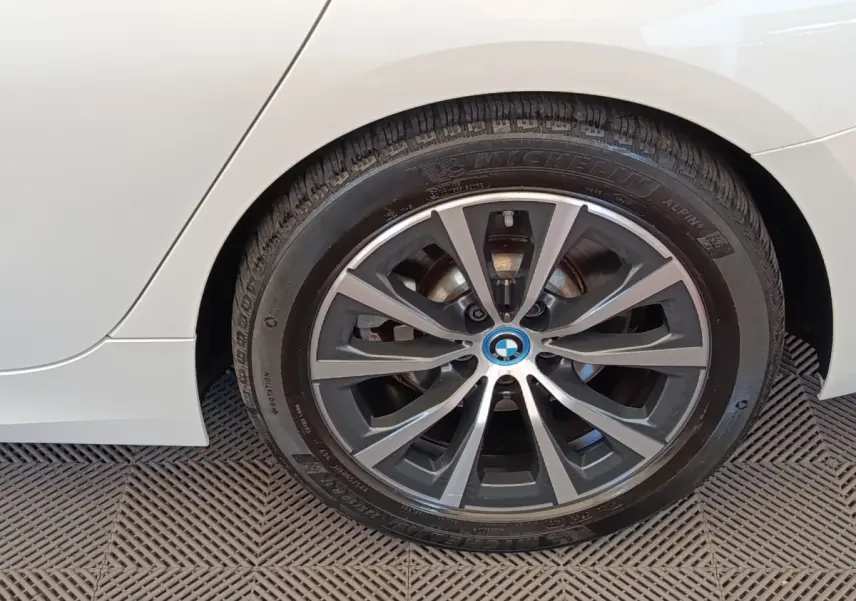 Gros plan sur la roue arrière droite d’une BMW Série 3 320e blanche avec jante alliage bicolore.