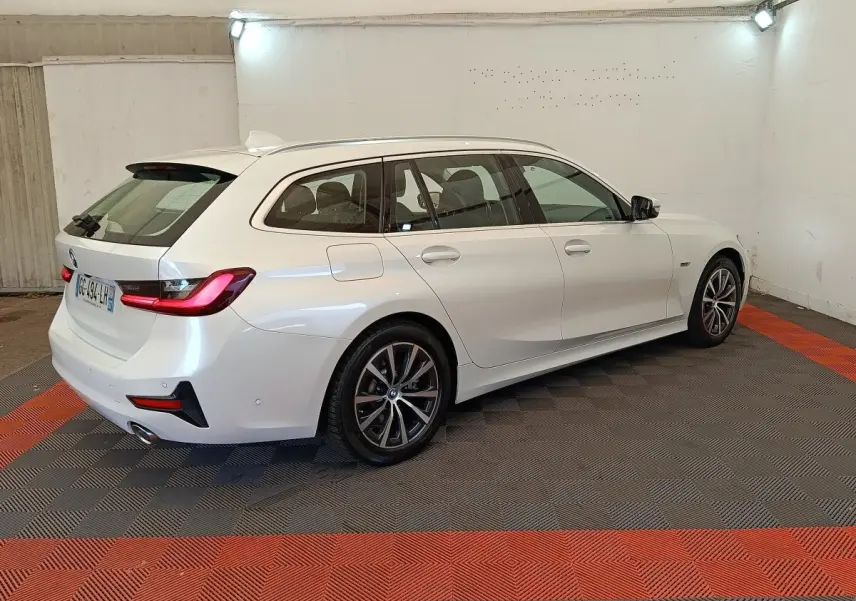 BMW Série 3 320e hybride blanche vue de trois quarts arrière droit, avec feux arrière LED et jantes alliage.