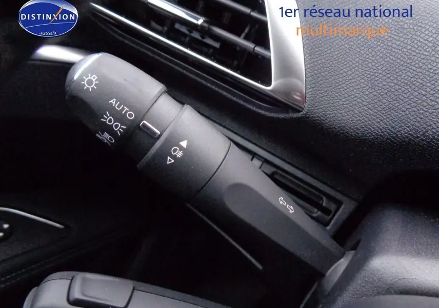 Gros plan sur la commande des phares et clignotants dans l'habitacle noir d'un Peugeot 3008 2023.