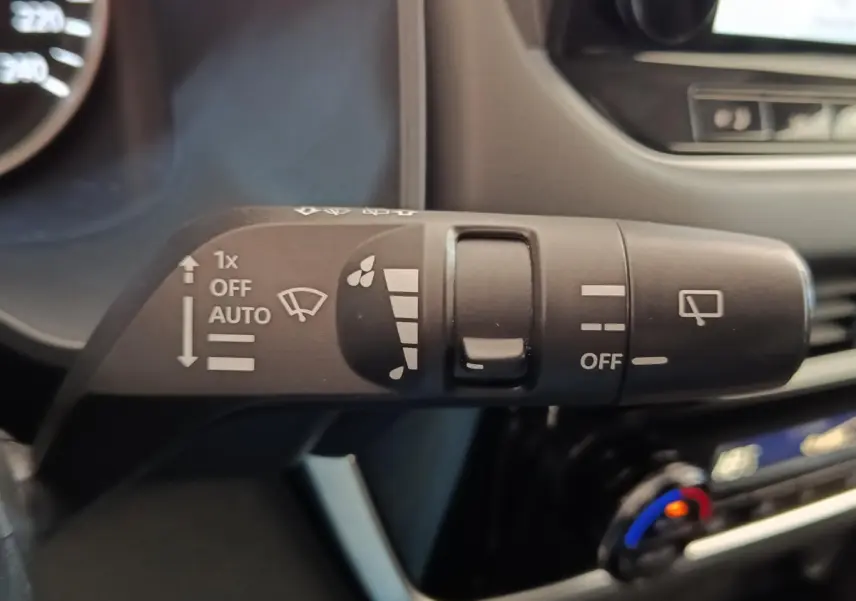 Gros plan sur la commande des essuie-glaces dans l’habitacle du Nissan Qashqai gris foncé, détails des symboles blancs visibles.