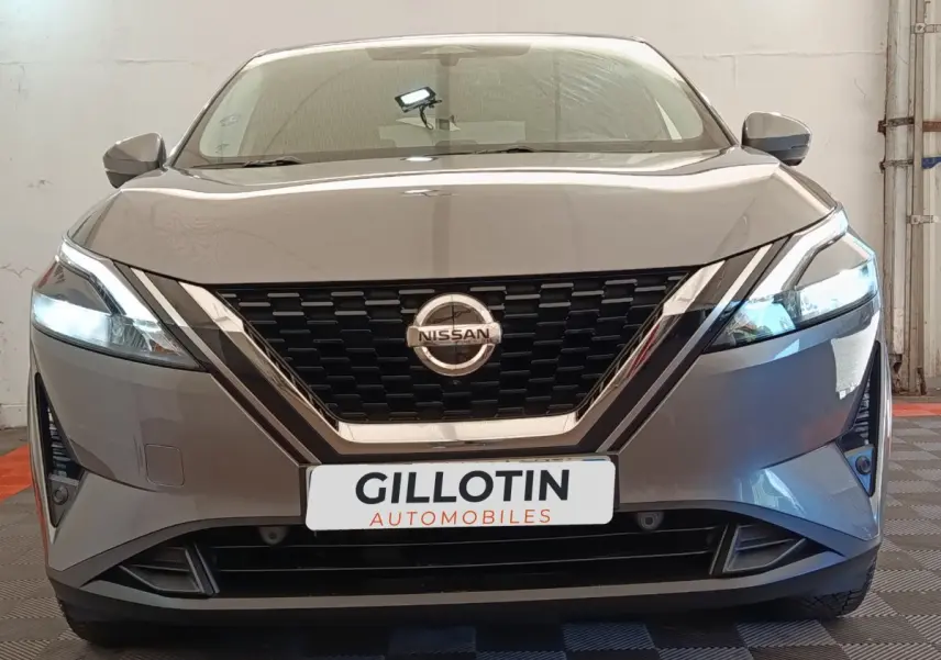Vue frontale d'un Nissan Qashqai gris foncé avec phares LED allumés et calandre noire brillante.