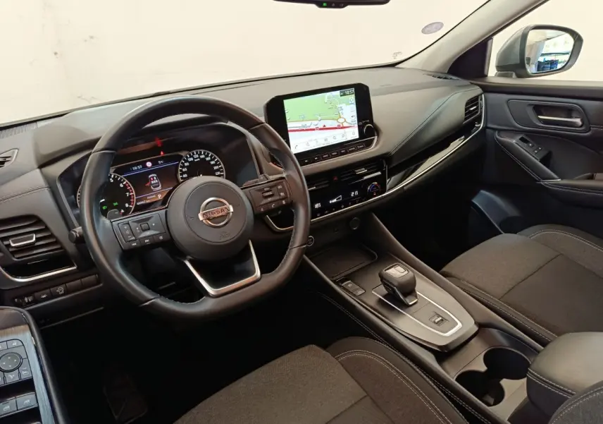 Vue intérieure côté conducteur du Nissan Qashqai 2022 avec tableau de bord noir et écran tactile central affichant la navigation.