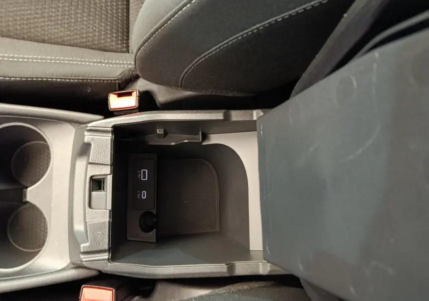 Vue plongeante sur la console centrale du Nissan Qashqai gris foncé, avec ports USB et porte-gobelets visibles.