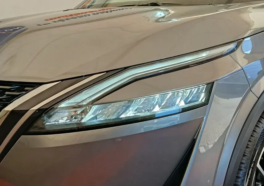 Gros plan sur le phare avant droit du Nissan Qashqai gris foncé, mettant en valeur son design LED moderne.