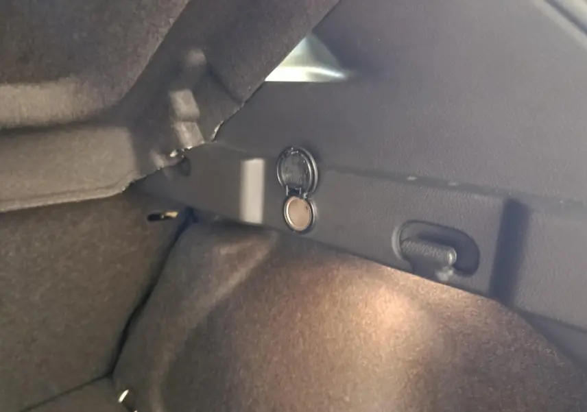 Détail du coffre du Nissan Qashqai gris foncé 2022 avec prise 12V et éclairage intérieur visible.