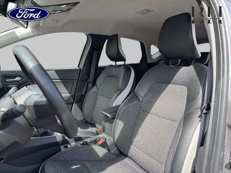 Vue intérieure côté conducteur du Renault Captur gris Cassiopée, mettant en valeur les sièges tissu et cuir avec accoudoir central.